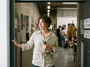Jeune femme curieuse devant une école d'art avec carnet